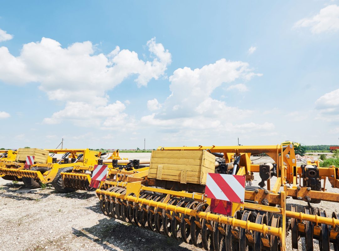 Close up of seeder attached to tractor in field. Agricultural machinery for spring works sowing